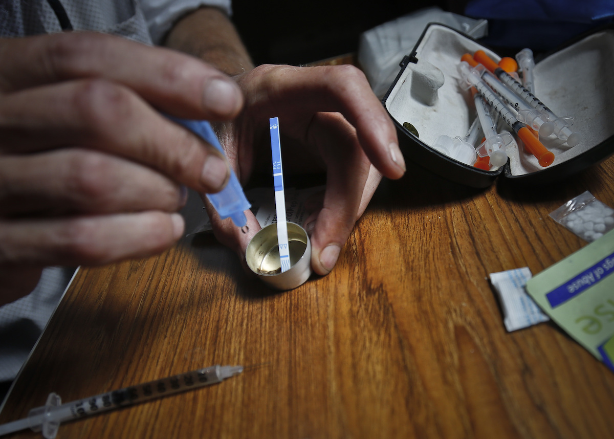 SPANISH: person using test stip to check contamination of fentnayl