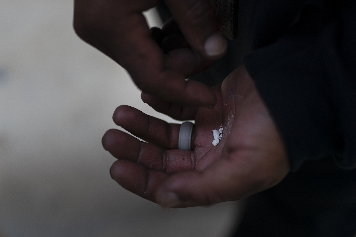 Hands holding pieces of a fentanyl pill
