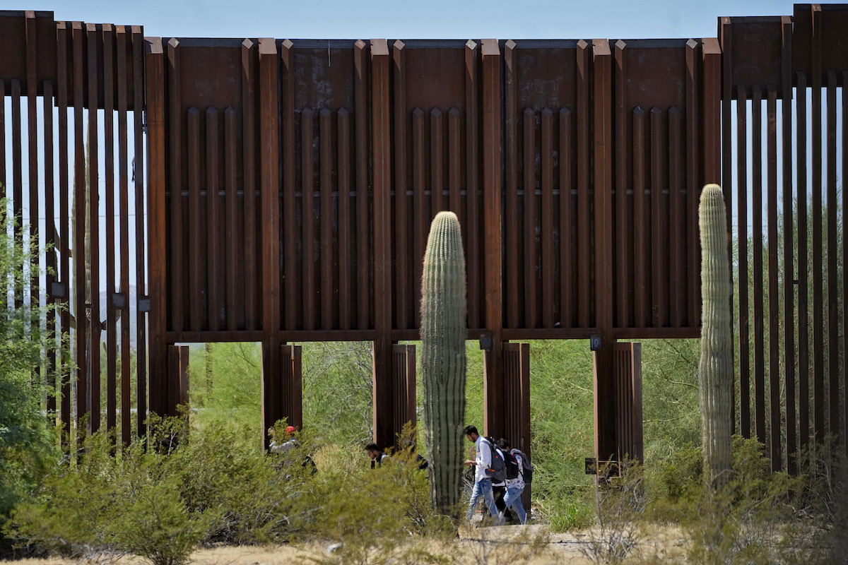 Group of migrants walk by open stormgates border Arizona, 8-29-2023