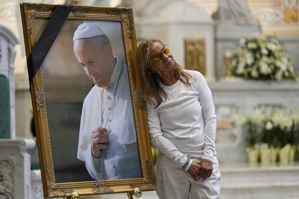 Woman leans on portrait of Pope Francis