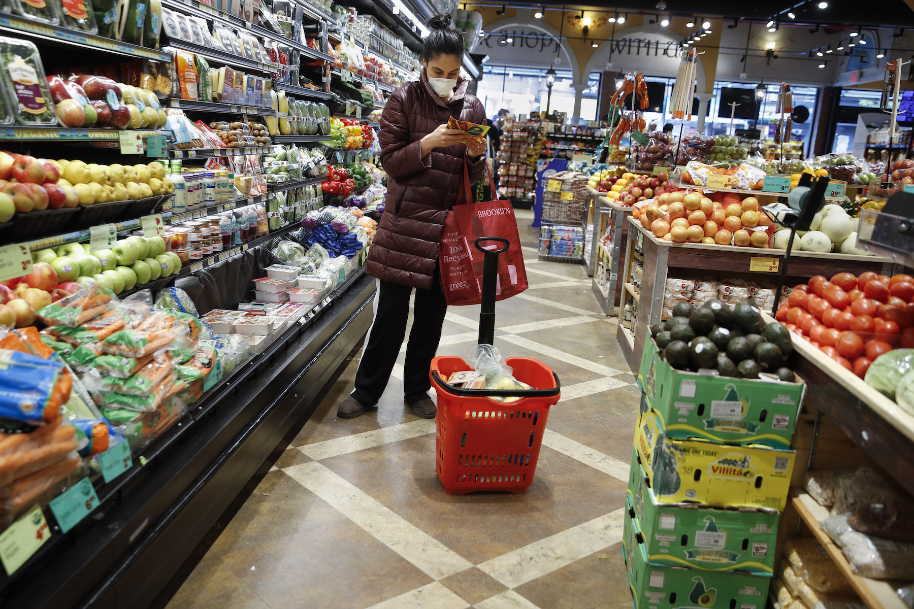 Masked woman in grocery reading products