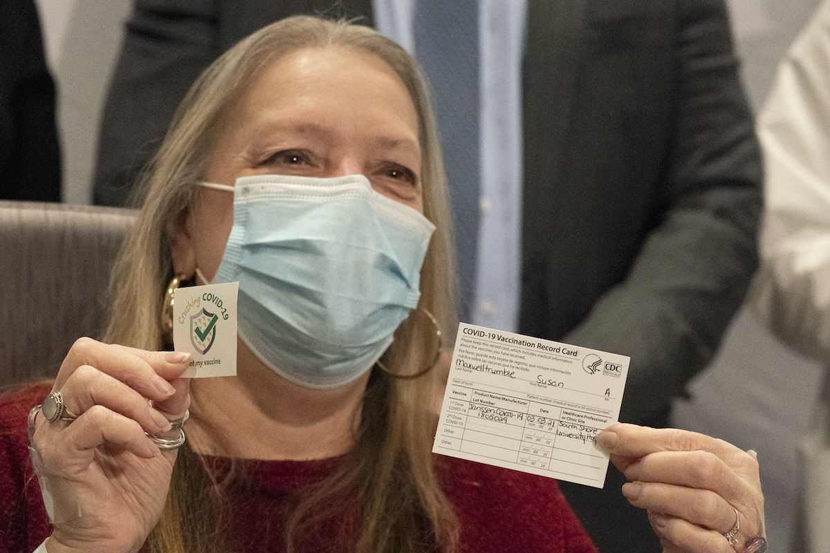 vaccinate woman holds up card