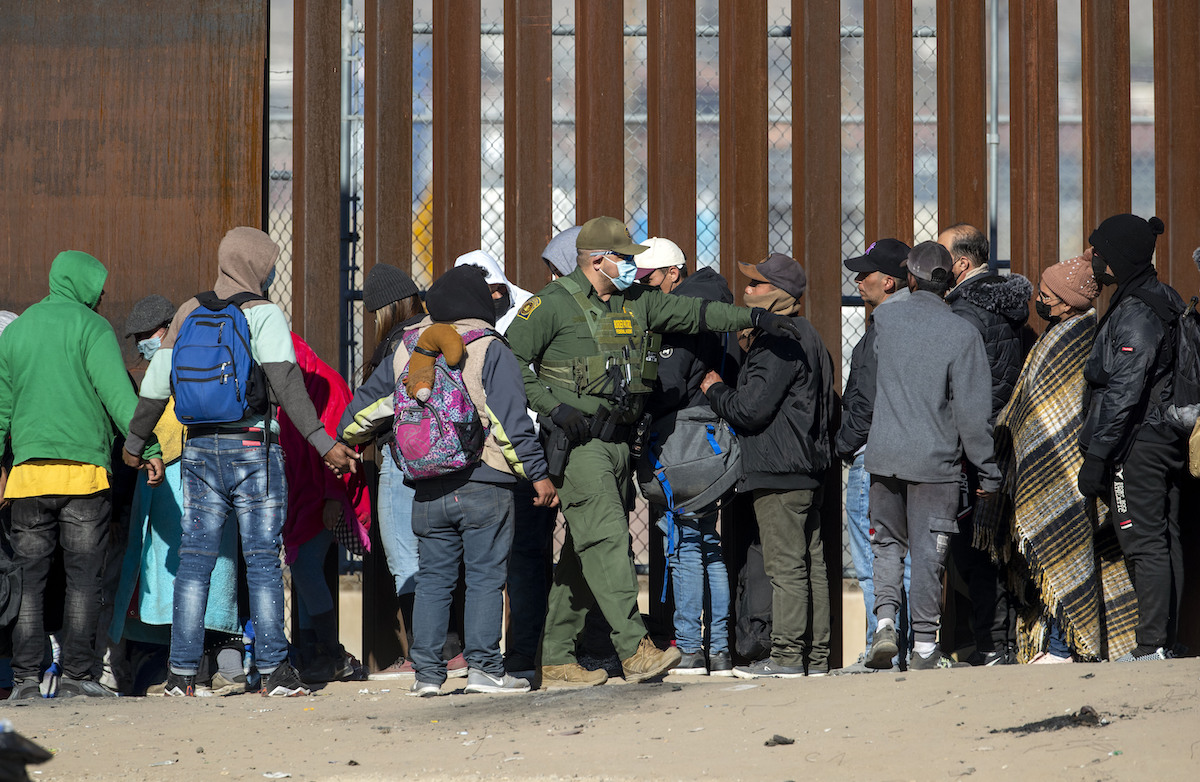 Border patrol agent with a line of immigrants at the border in Dec. 2022