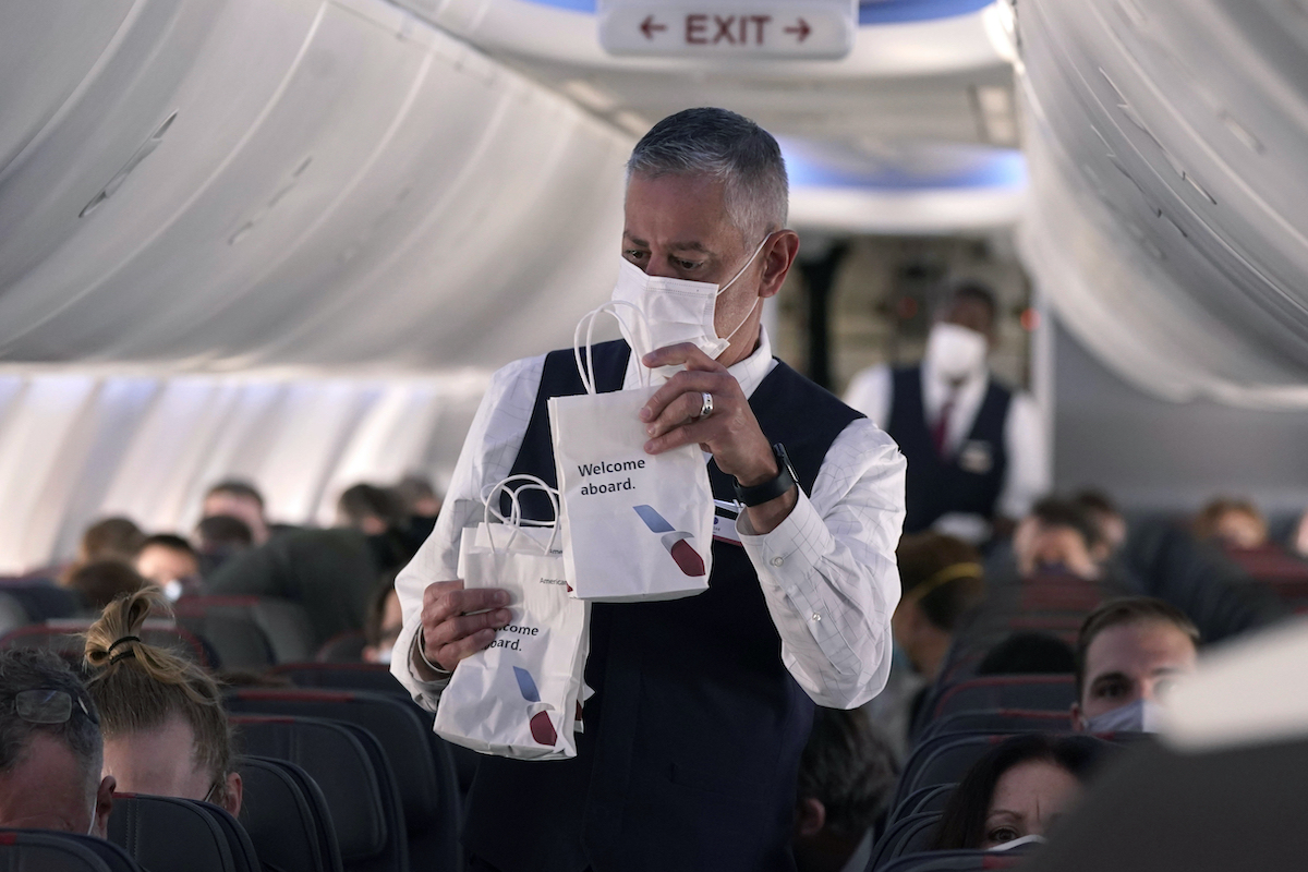 An American Airlines flight attendant hands out snack bags aboard a Boeing 737 Max jet before taking off from Dallas Fort Worth airport in Grapevine, Texas, Wednesday, Dec. 2, 2020. (AP)