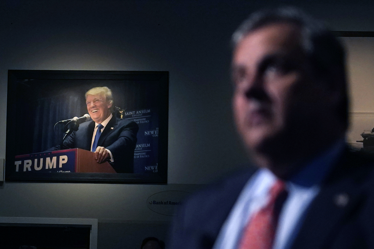 Chris Christie in NH 6-6-23 with portrait of Trump in background