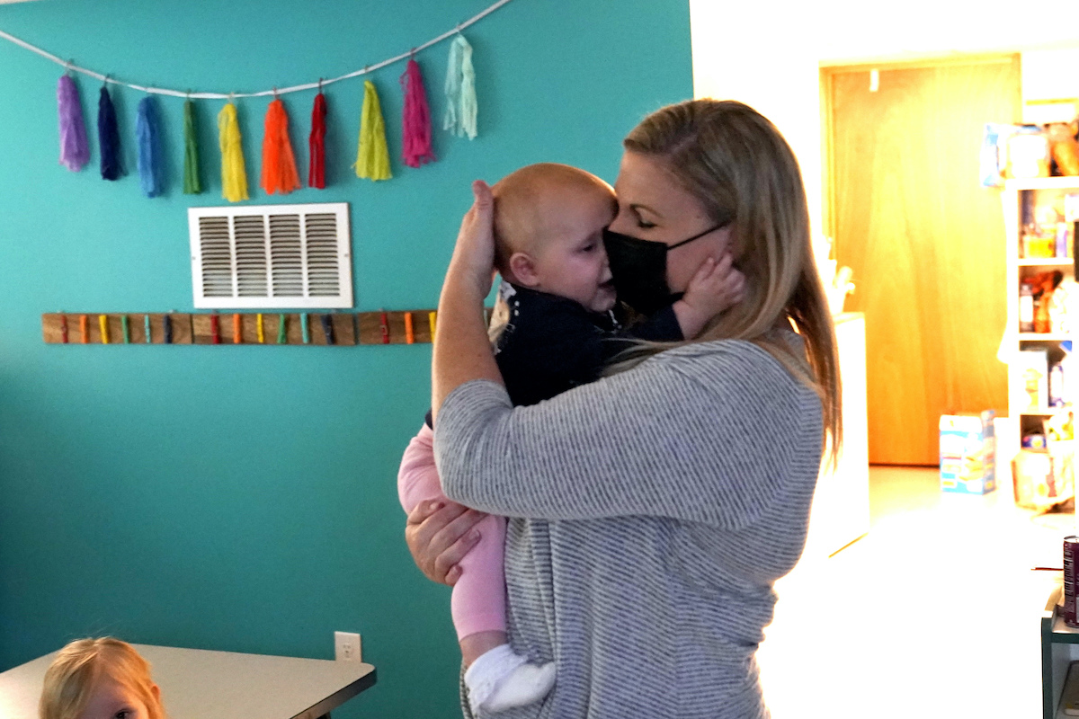 Woman cuddles baby at daycare center