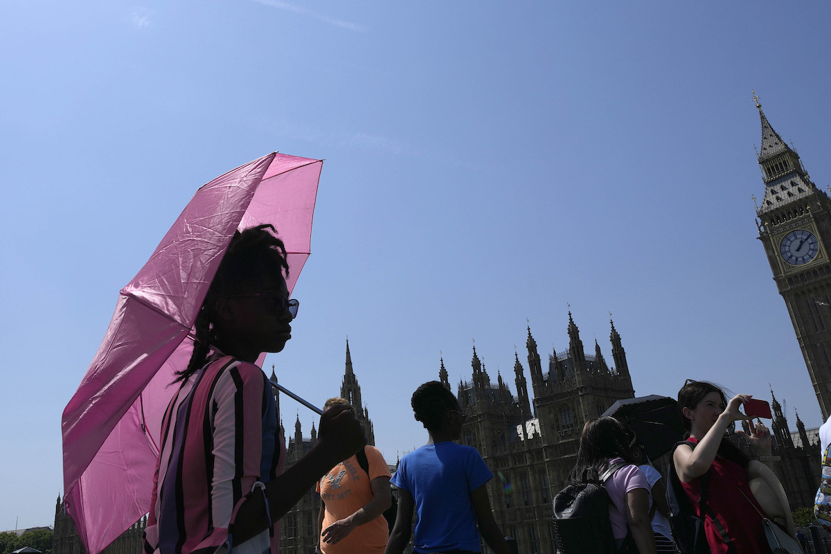 Woman in UK holding pink umbrella in heat wave