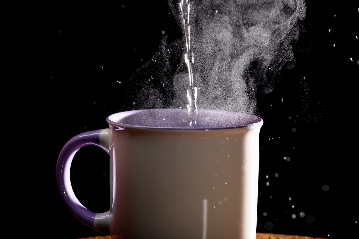 Photo of hot water being poured into cup on black background