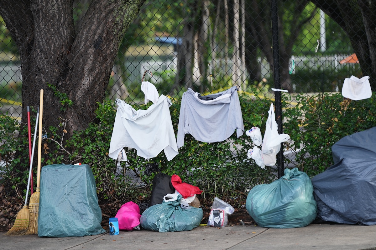 Homeless people's bags hanging from a fence in Miami