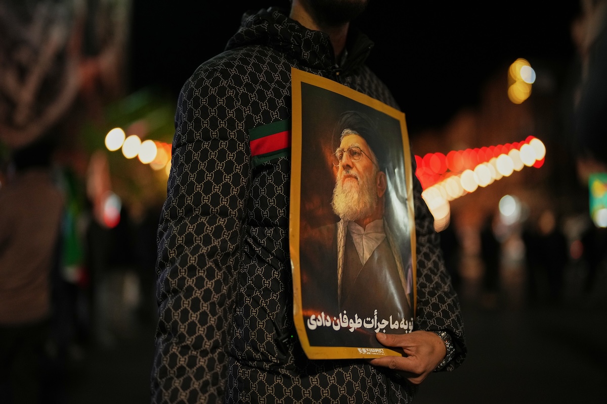 Man holding photo of Ayatollah Ali Khamenei 04-05-26