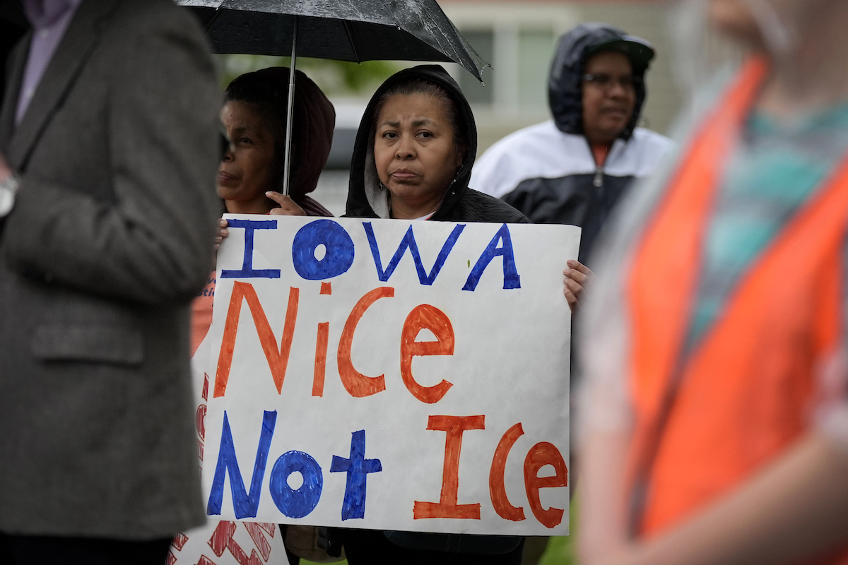 Woman holds an ICE demonstration sign Iowa immigration justice march in May 2024.